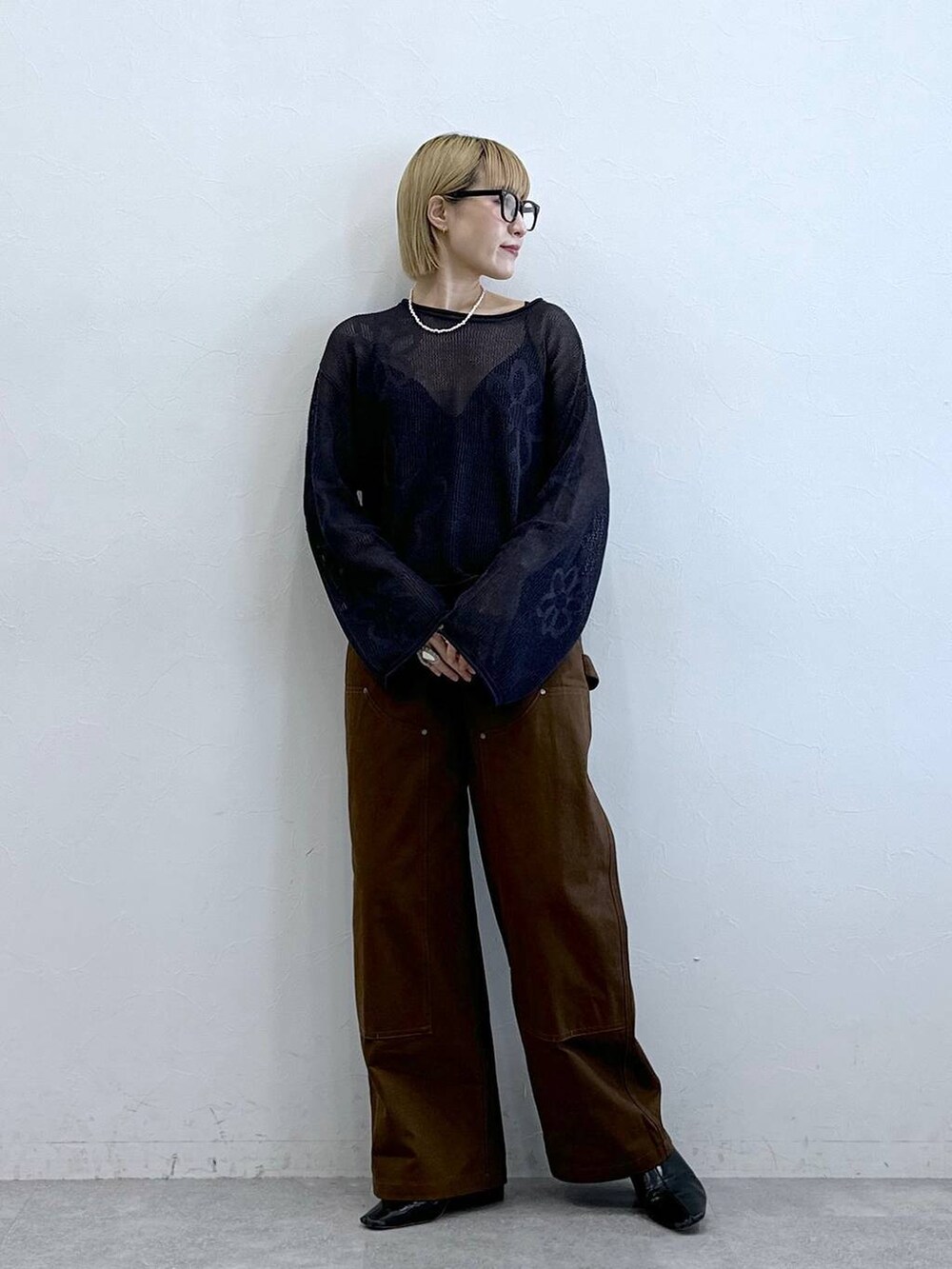 グレー系のニット/セーター、ブラウン系のチノパンツ、グレー系のメガネを着用したレディースの夏コーディネートの2枚目の写真