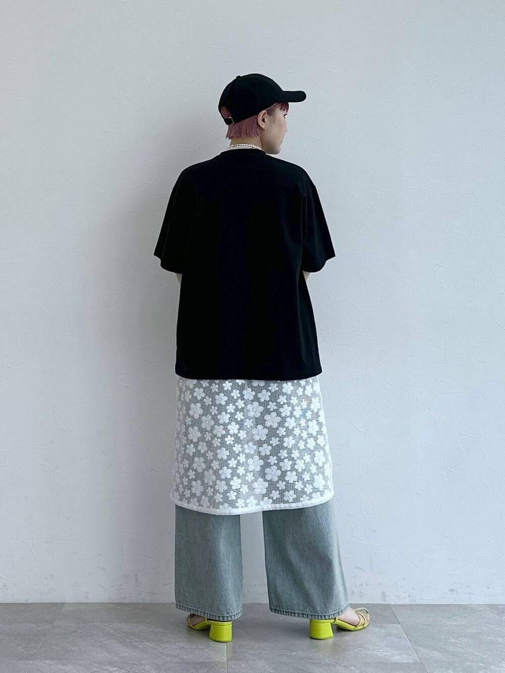ブルー系のデニムパンツ、ホワイト系のワンピース、ブラック系のTシャツ/カットソーを着用したレディースの春コーディネートの7枚目の写真