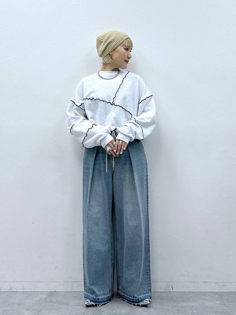 シルバー系のパンプス、ブルー系のデニムパンツ、ホワイト系のスウェットを着用したレディースの秋コーディネートの3枚目の写真