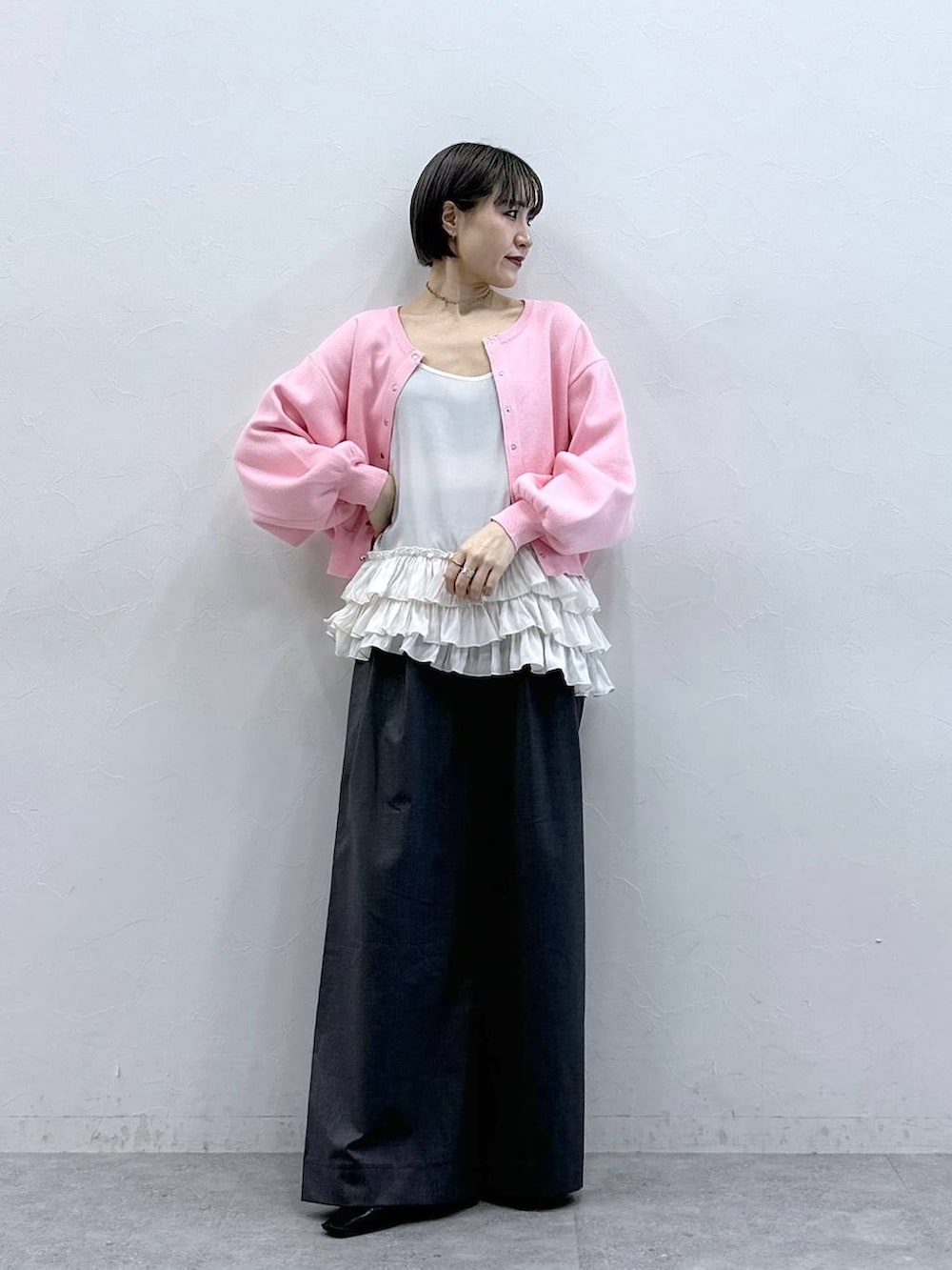 ホワイト系のキャミソール、ピンク系のカーディガン/ボレロ、グレー系のスラックスを着用したレディースの春コーディネートの4枚目の写真