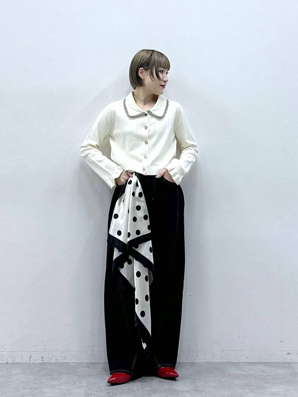 レッド系のパンプス、ホワイト系のカーディガン/ボレロ、ブラック系のデニムパンツを着用したレディースの冬コーディネートの2枚目の写真