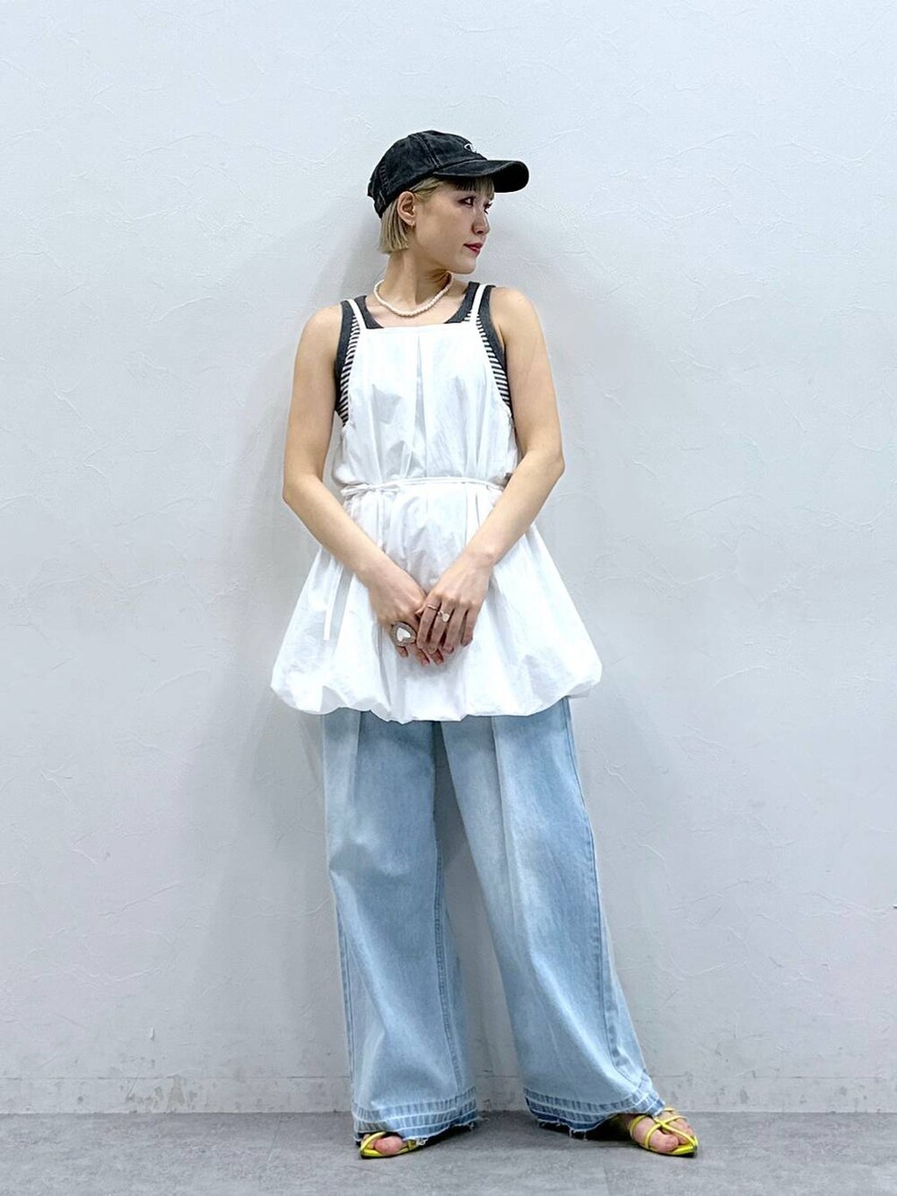 グレー系のタンクトップ、ブルー系のデニムパンツ、ホワイト系のワンピースを着用したレディースの夏コーディネートの4枚目の写真