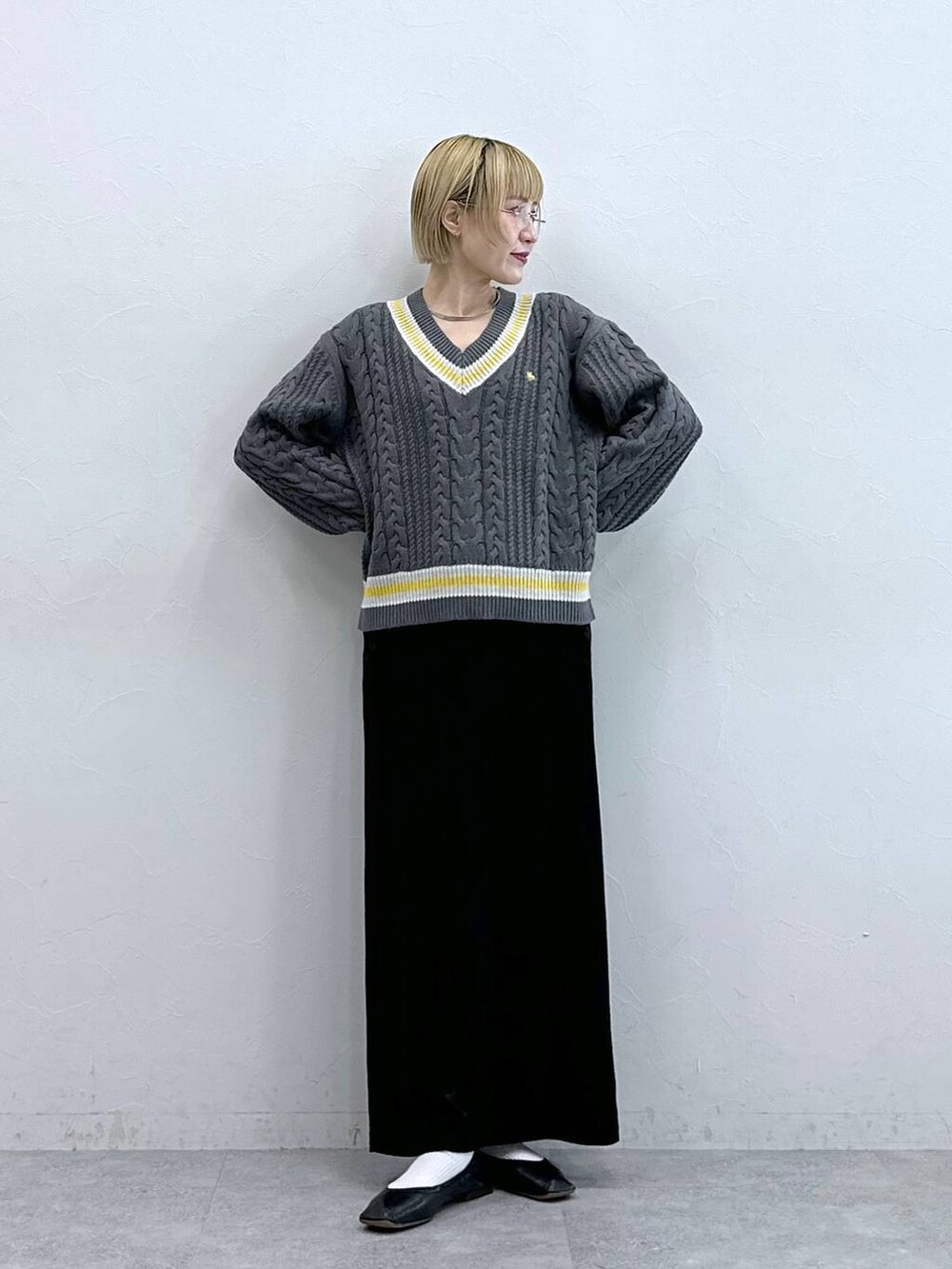 グレー系のニット/セーター、ブラック系のスカートを着用したレディースの秋コーディネートの2枚目の写真