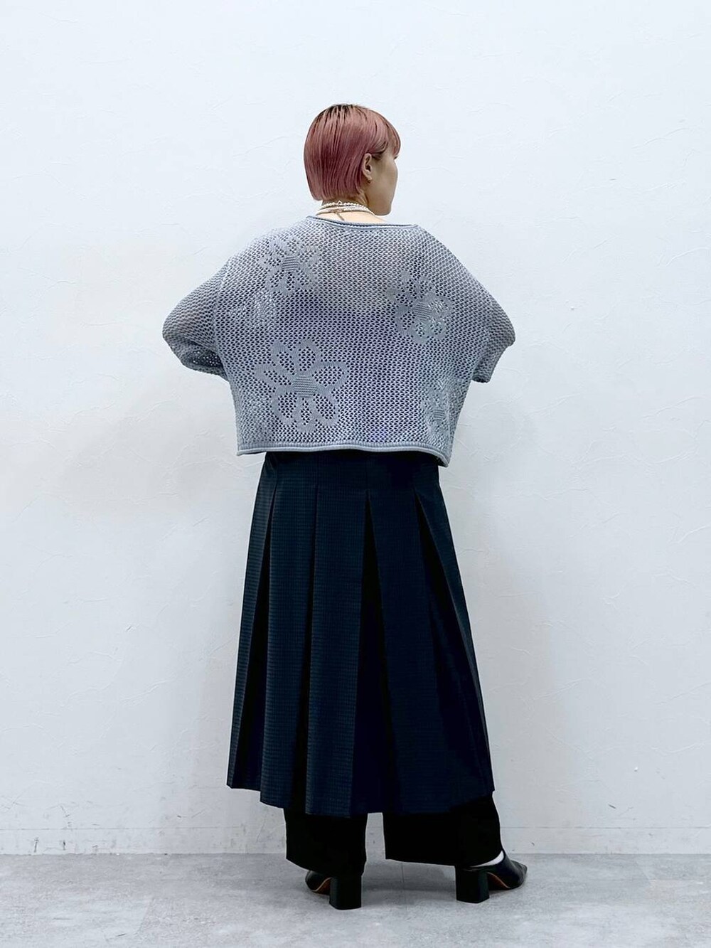 ブラック系のスラックス、ブルー系のニット/セーター、グレー系のスカートを着用したレディースの春コーディネートの5枚目の写真