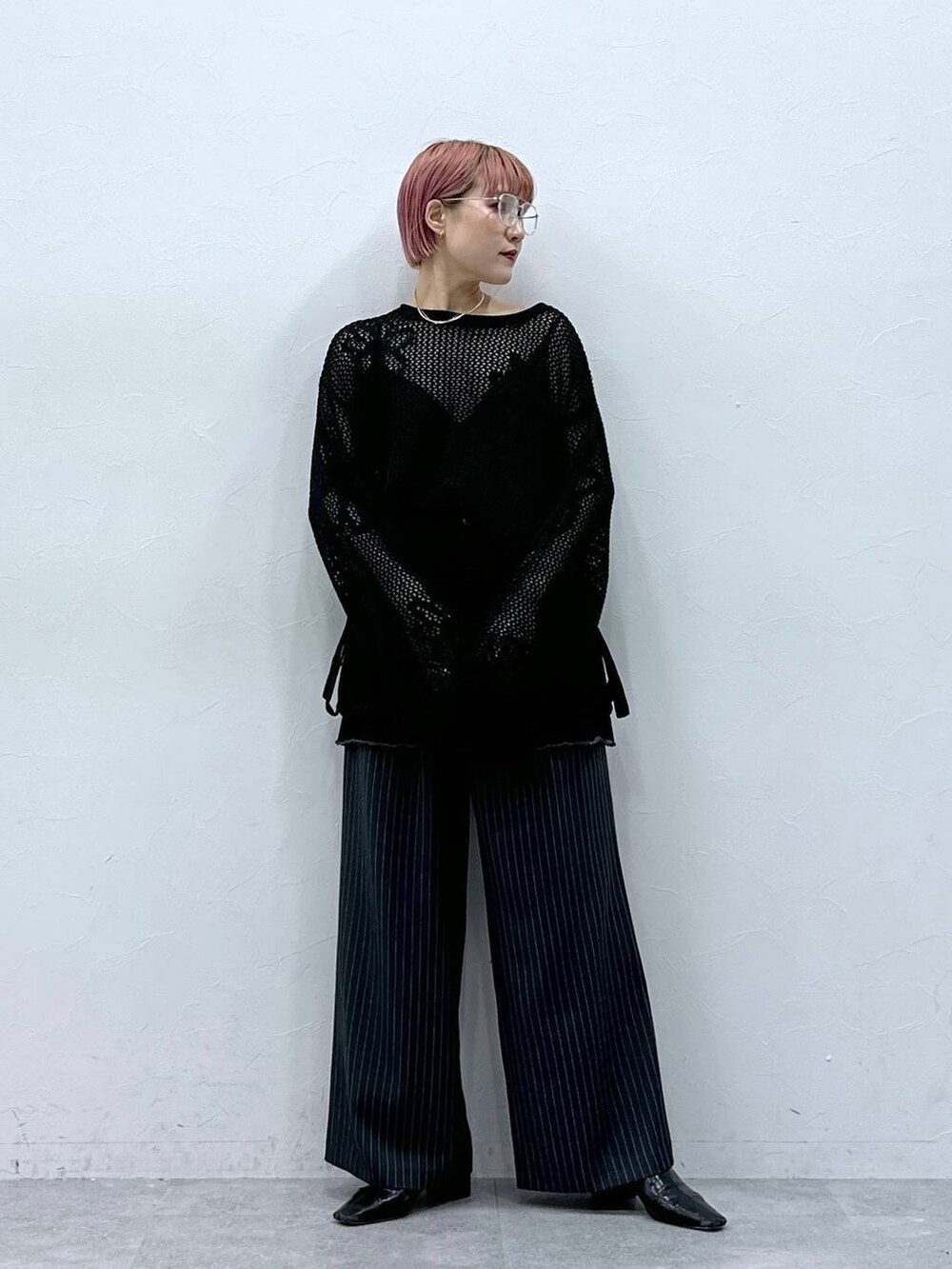 グレー系のスラックス、ブラック系のニット/セーター、ブラック系のスカートを着用したレディースの春コーディネートの2枚目の写真