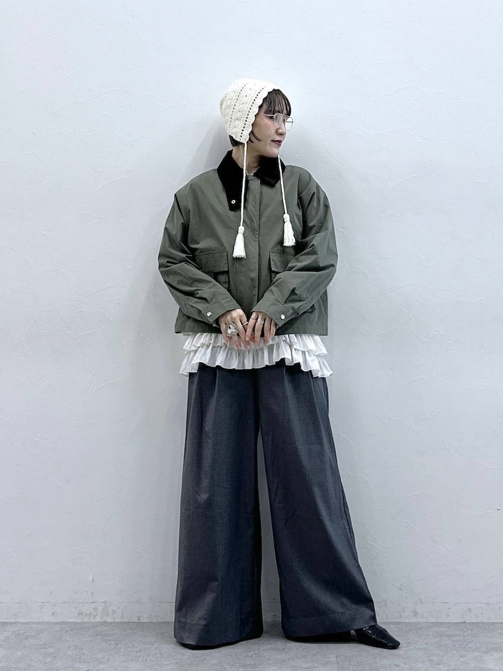 ホワイト系のキャミソール、グリーン系のブルゾン、グレー系のスラックスを着用したレディースの春コーディネートの3枚目の写真