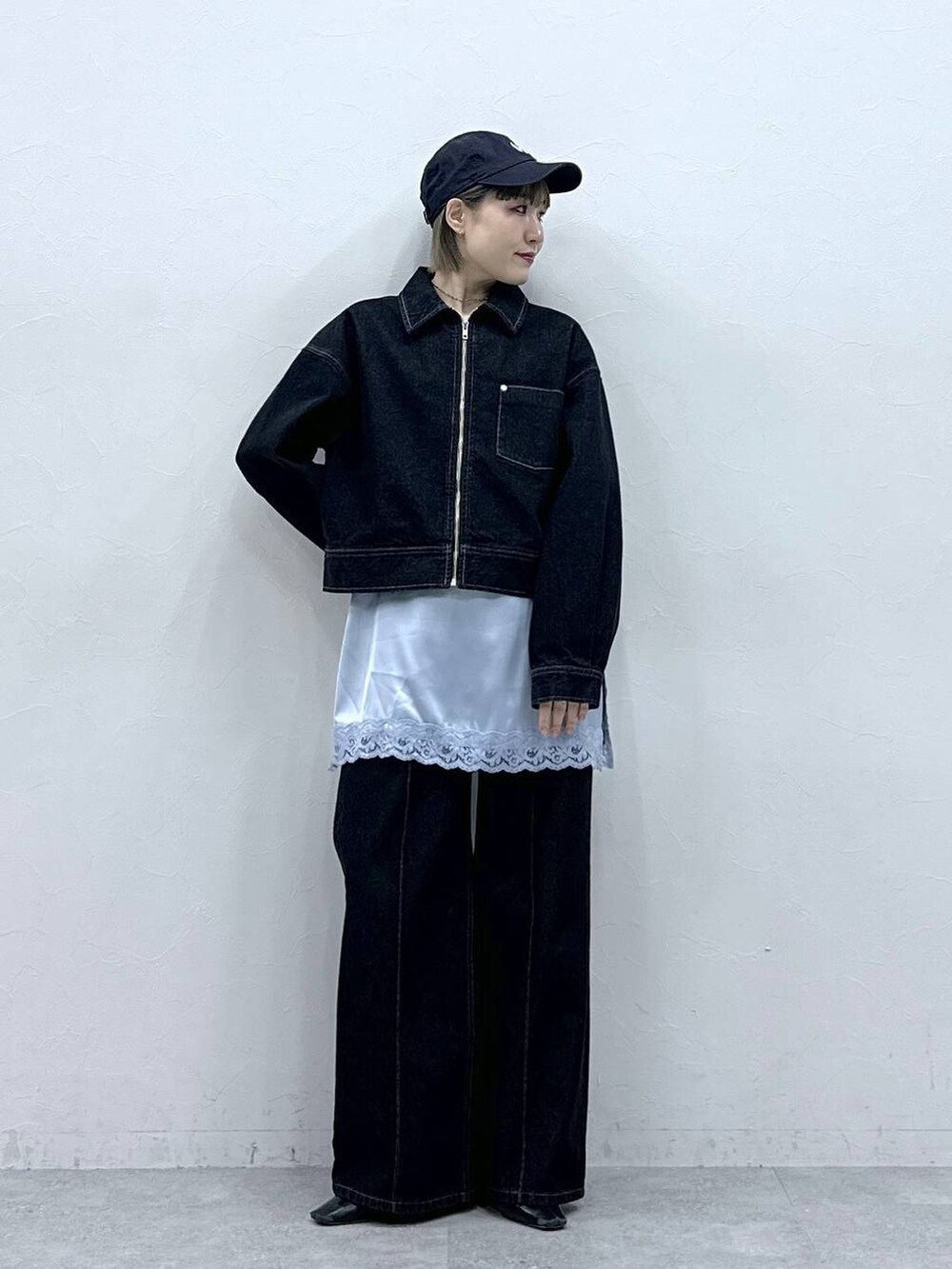 ブラック系のデニムジャケット、ブラック系のデニムパンツ、ブルー系のキャミソールを着用したレディースの冬コーディネートの2枚目の写真