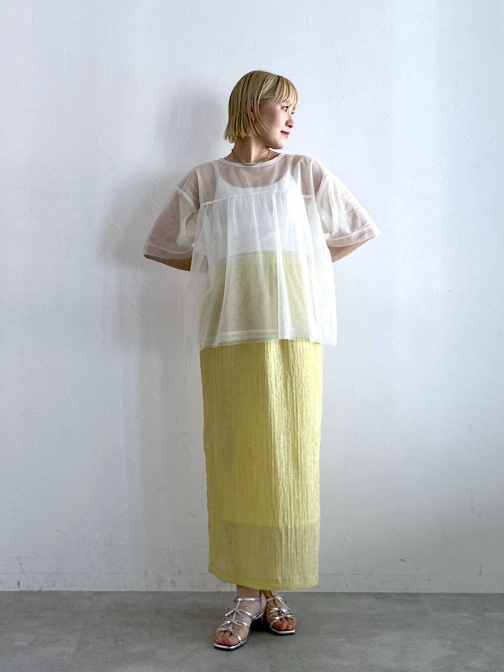 シルバー系のサンダル、イエロー系のスカート、ホワイト系のTシャツ/カットソーを着用したレディースの夏コーディネートの3枚目の写真