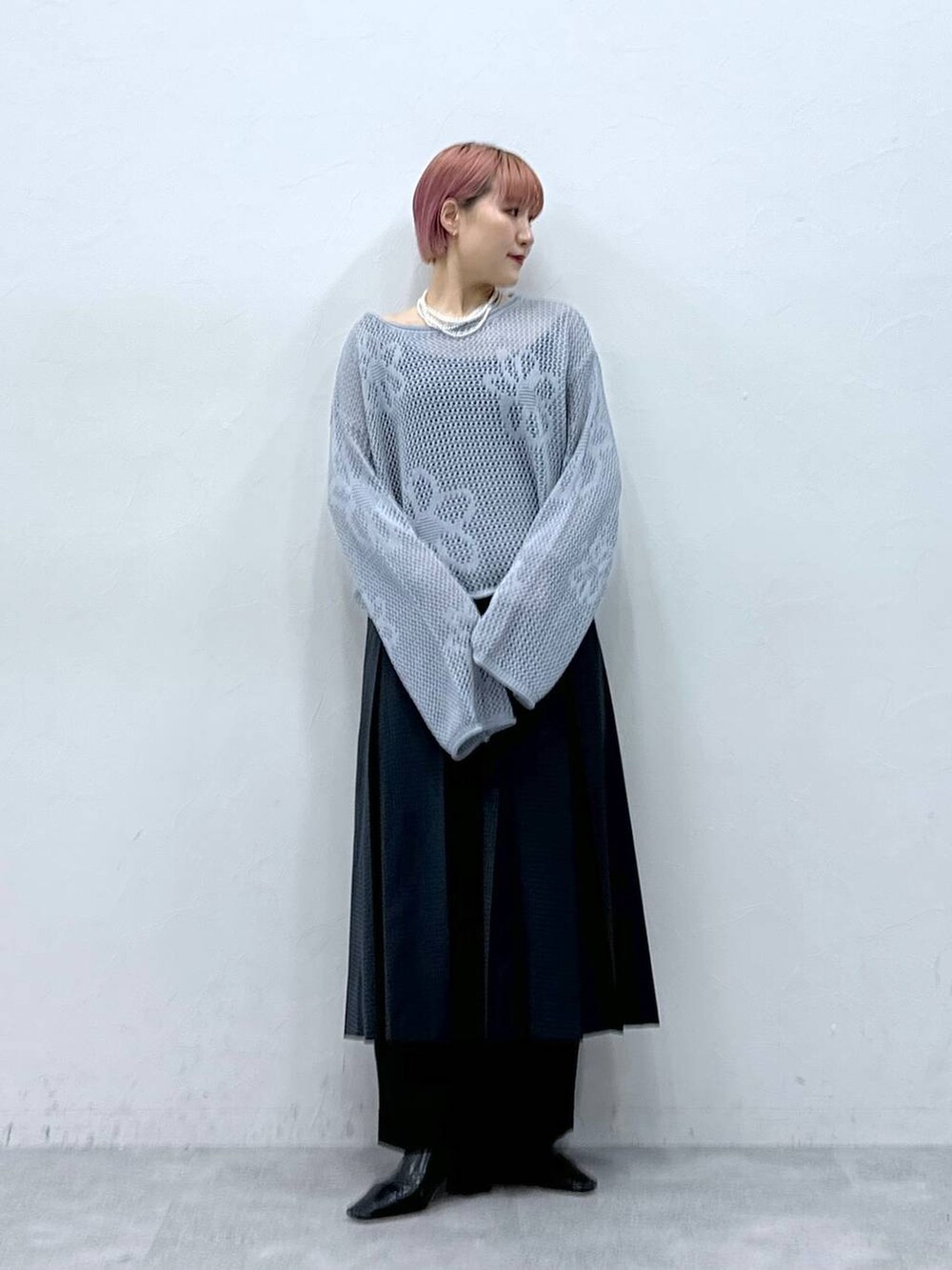 ブラック系のスラックス、ブルー系のニット/セーター、グレー系のスカートを着用したレディースの春コーディネートの3枚目の写真