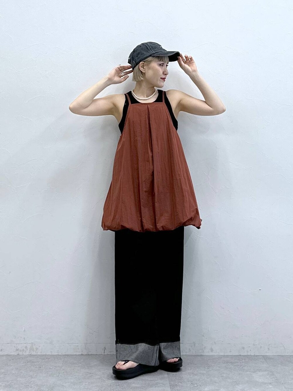 ブラウン系のワンピース、ブラック系のデニムパンツ、ブラック系のキャップを着用したレディースの夏コーディネートの3枚目の写真