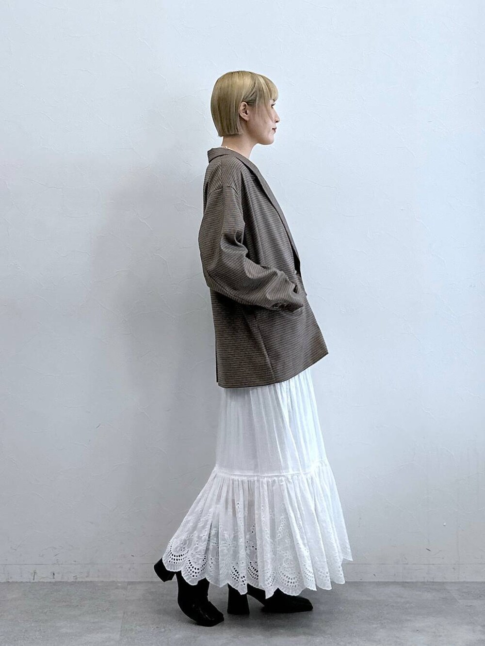 ブラウン系のテーラードジャケット、ホワイト系のスカート、ブラック系のブラジャーを着用したレディースの秋コーディネートの4枚目の写真