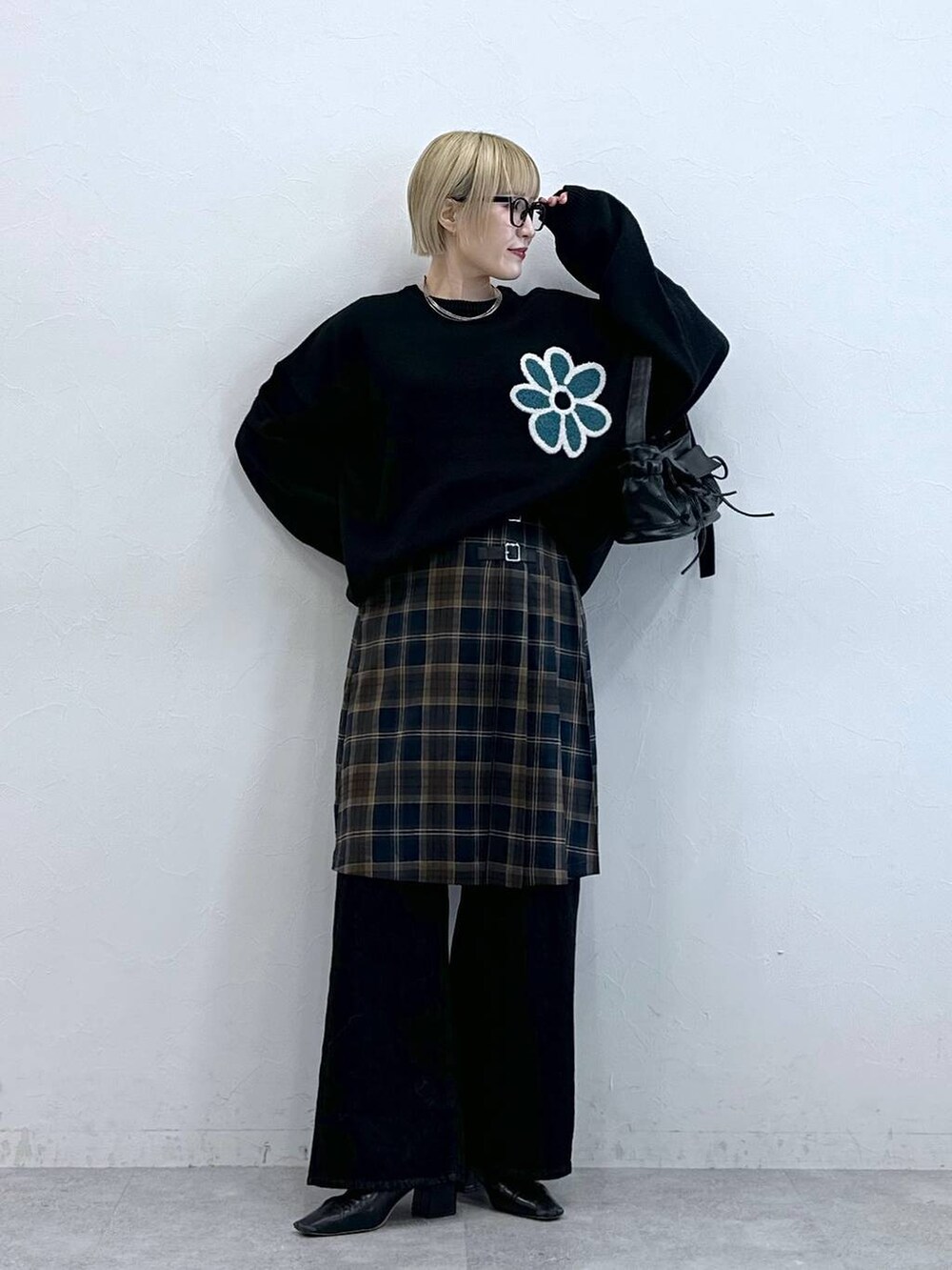 ブラック系のニット/セーター、ブラック系のデニムパンツ、ブラウン系のスカートを着用したレディースの秋コーディネートの3枚目の写真