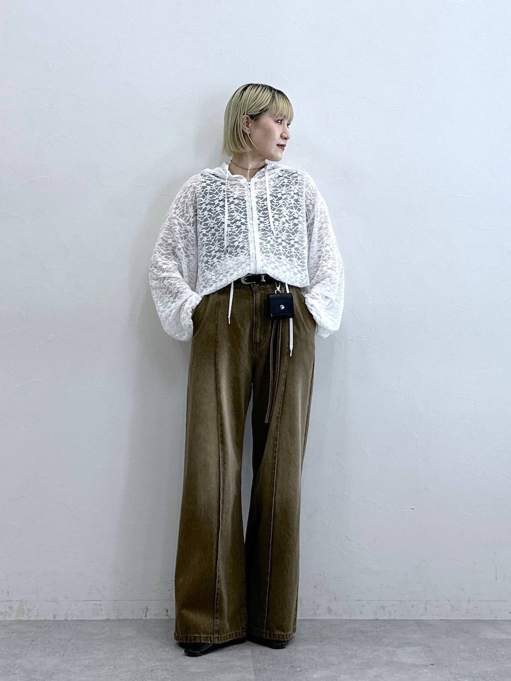 ホワイト系のパーカー、ブラウン系のデニムパンツ、ブラック系のベルトを着用したレディースの夏コーディネートの2枚目の写真