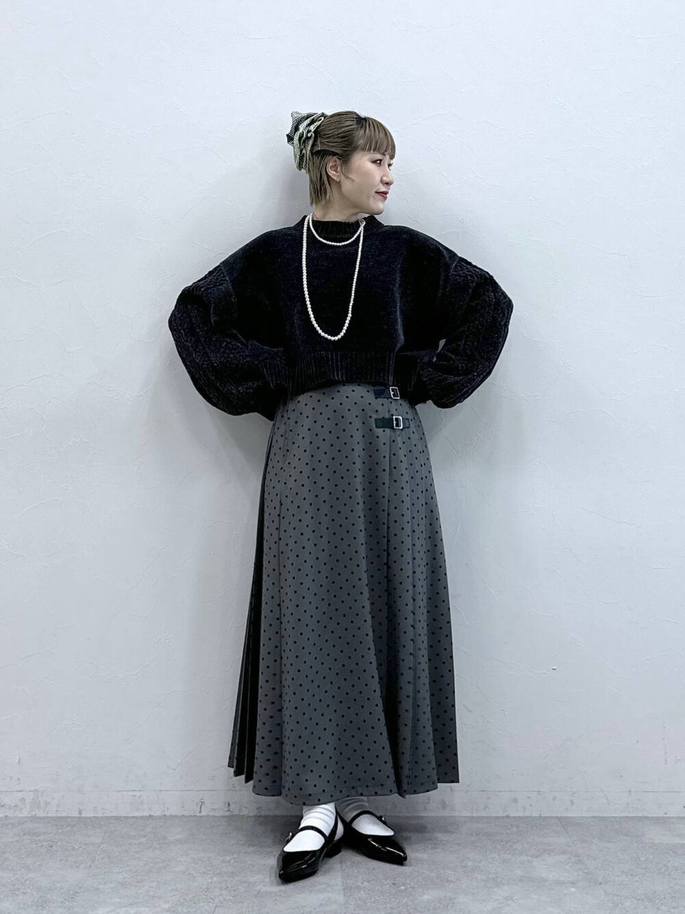 ブラック系のニット/セーター、ブラック系のパンプス、グレー系のスカートを着用したレディースの冬コーディネートの2枚目の写真