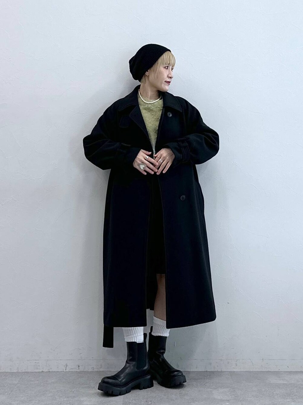 ブラック系のスラックス、イエロー系のニット/セーター、ブラック系のブーツを着用したレディースの秋コーディネートの5枚目の写真