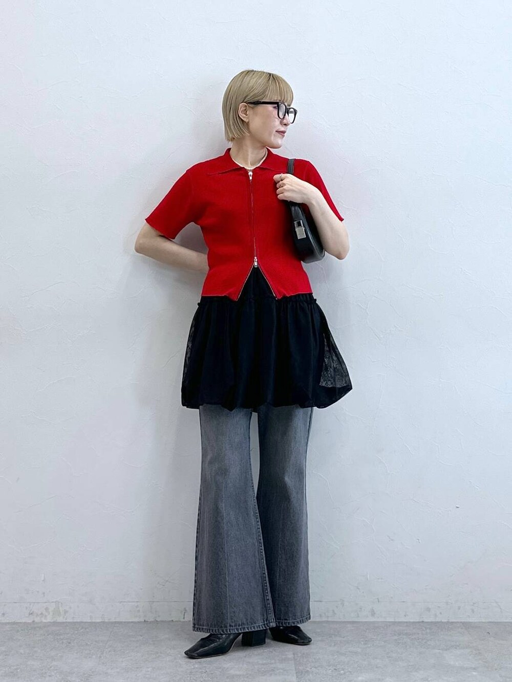 レッド系のニット/セーター、グレー系のデニムパンツ、ブラック系のスカートを着用したレディースの夏コーディネートの4枚目の写真