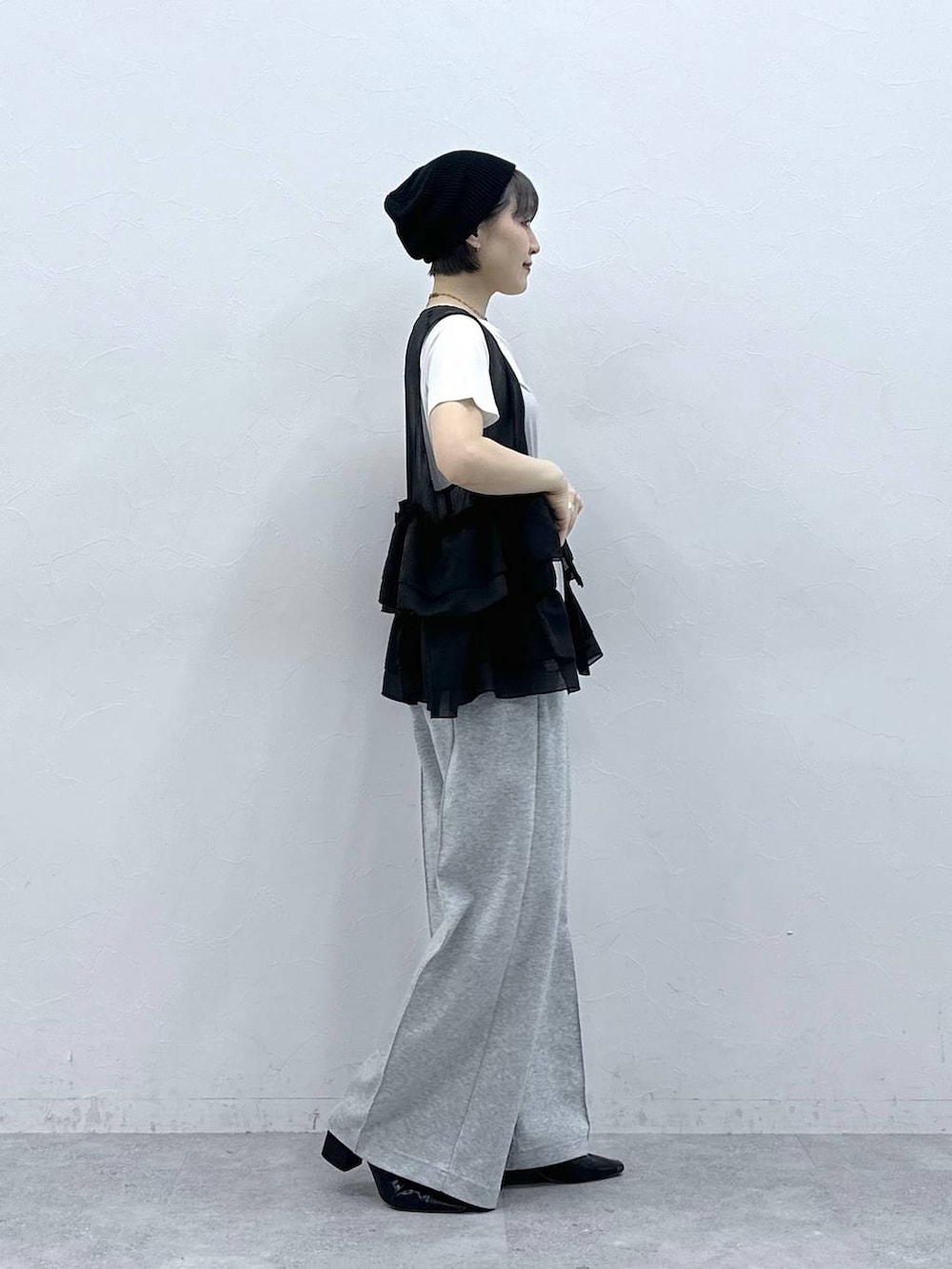 グレー系のスウェットパンツ、ホワイト系のTシャツ/カットソー、ブラック系のベストを着用したレディースの春コーディネートの7枚目の写真