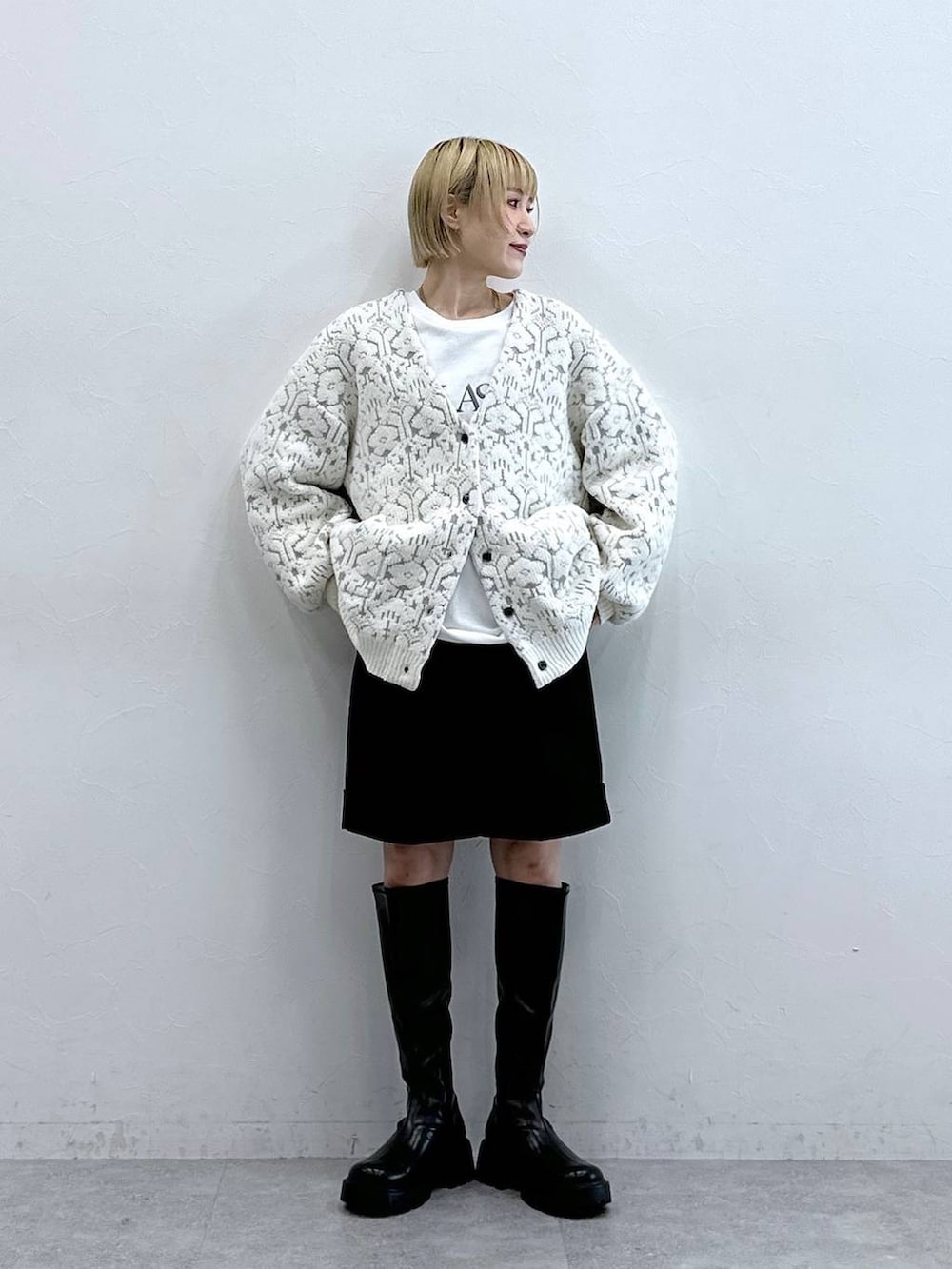 ブラック系のブーツ、ホワイト系のカーディガン/ボレロ、ブラック系のチノパンツを着用したレディースの秋コーディネートの3枚目の写真