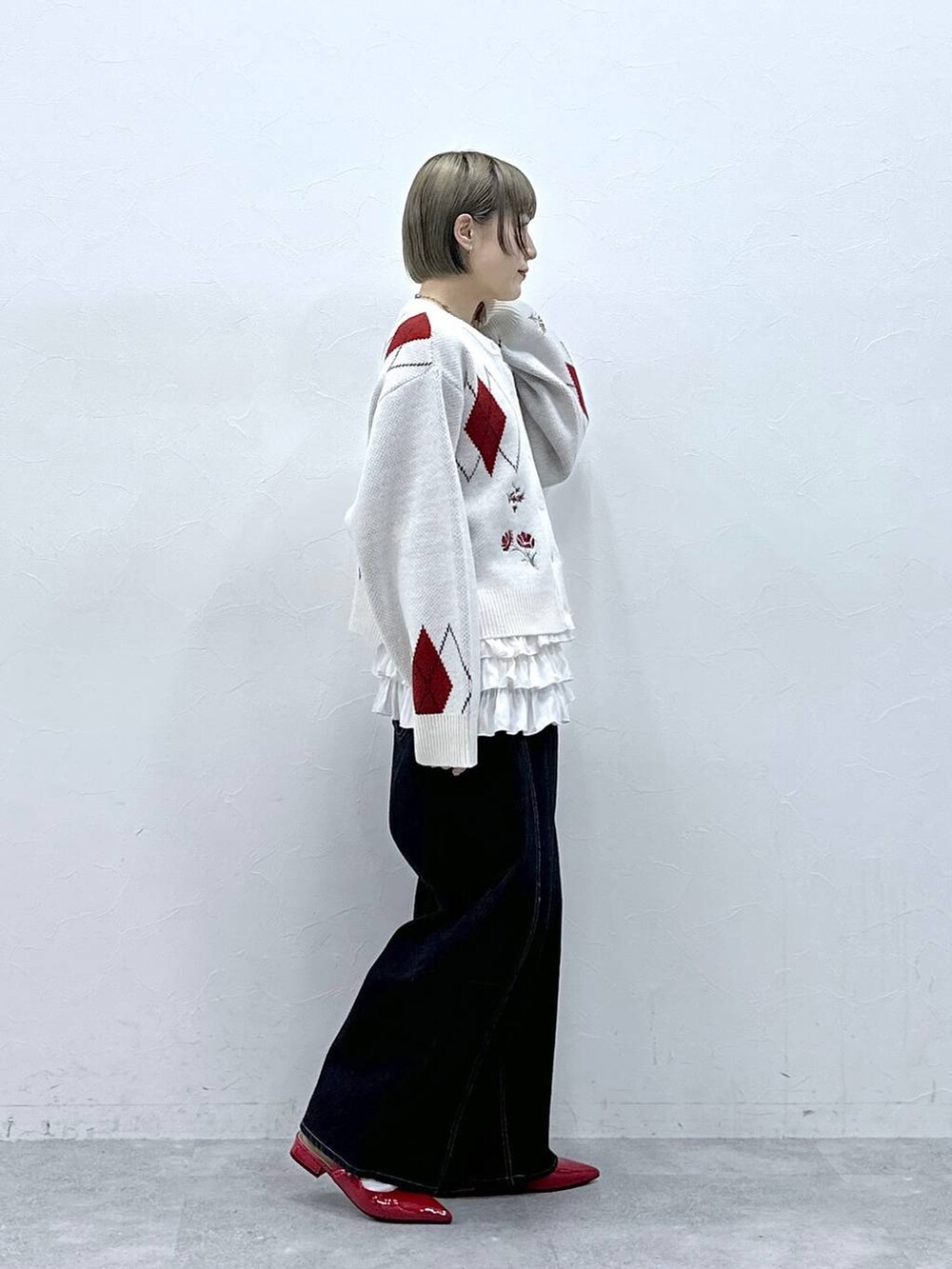 ホワイト系のキャミソール、レッド系のパンプス、ブラック系のデニムパンツを着用したレディースの冬コーディネートの4枚目の写真