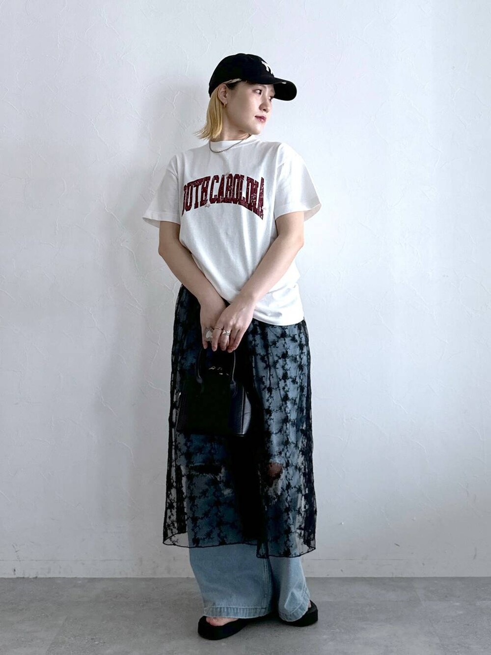 ブルー系のデニムパンツ、ブラック系のワンピース、ホワイト系のTシャツ/カットソーを着用したレディースの夏コーディネートの2枚目の写真