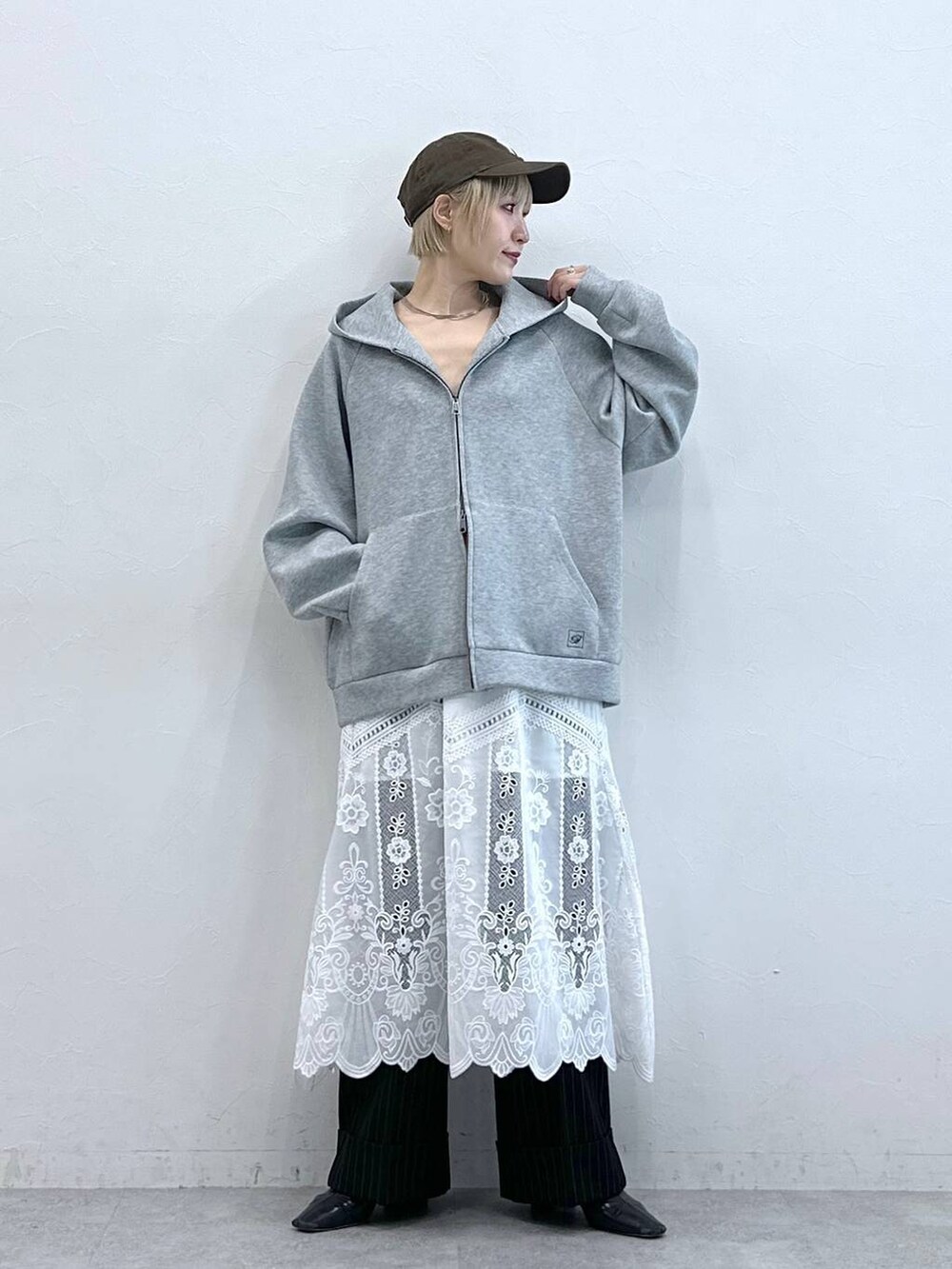 ブラウン系のスラックス、ホワイト系のスカート、グレー系のパーカーを着用したレディースの秋コーディネートの2枚目の写真