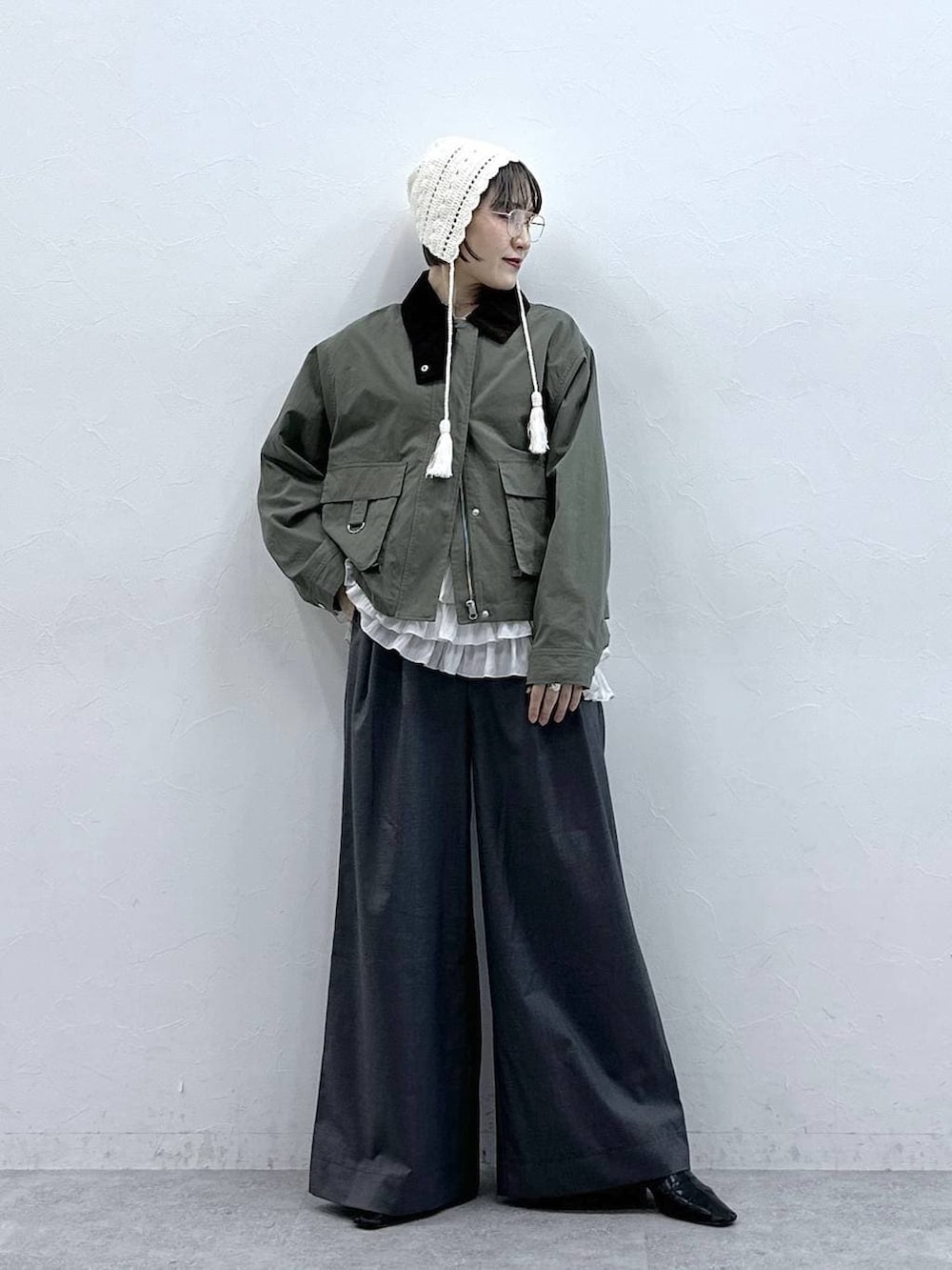 ホワイト系のキャミソール、グリーン系のブルゾン、グレー系のスラックスを着用したレディースの春コーディネートの2枚目の写真