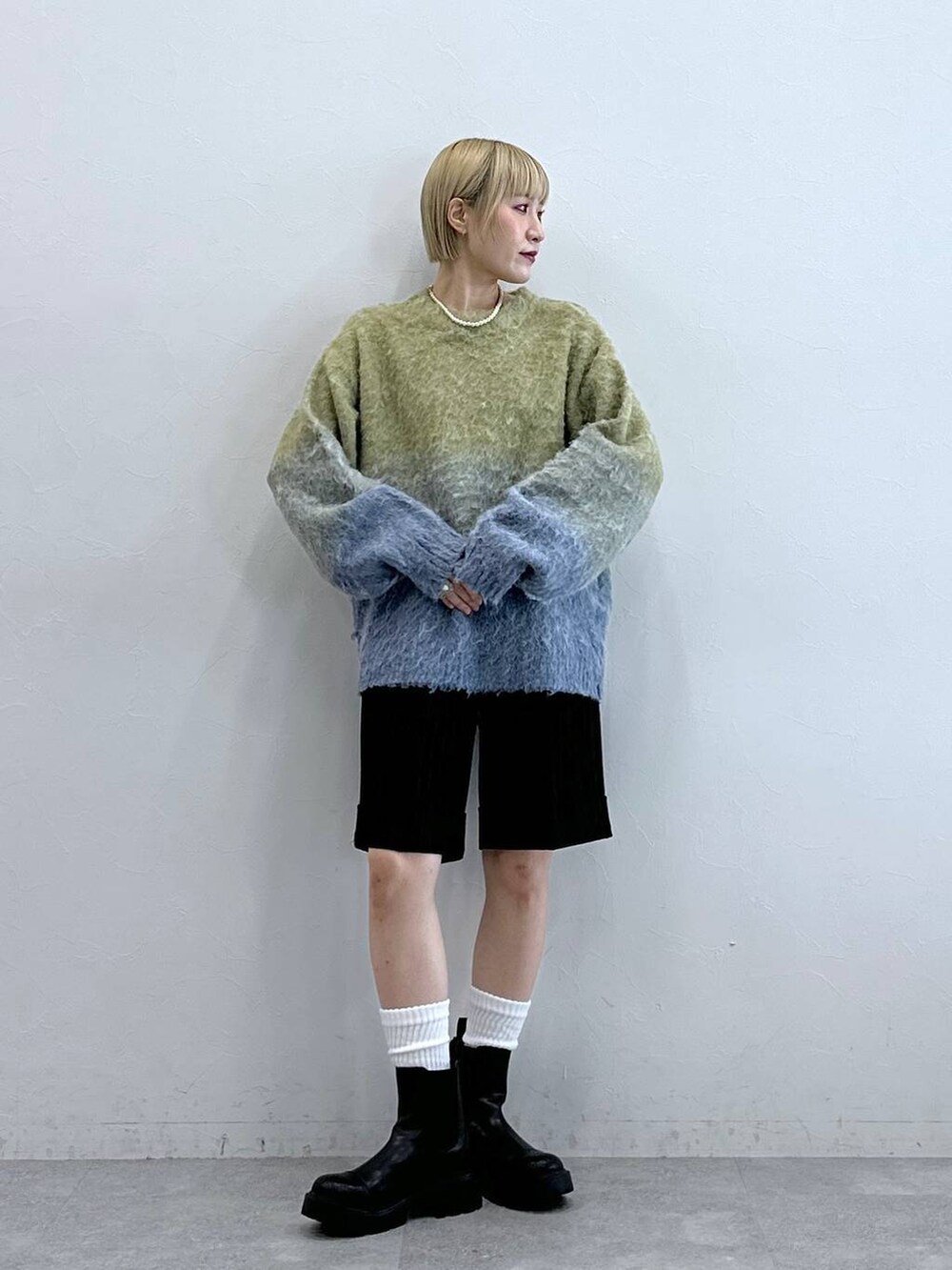 ブラウン系のスラックス、ブラック系のブーツ、イエロー系のニット/セーターを着用したレディースの秋コーディネートの2枚目の写真