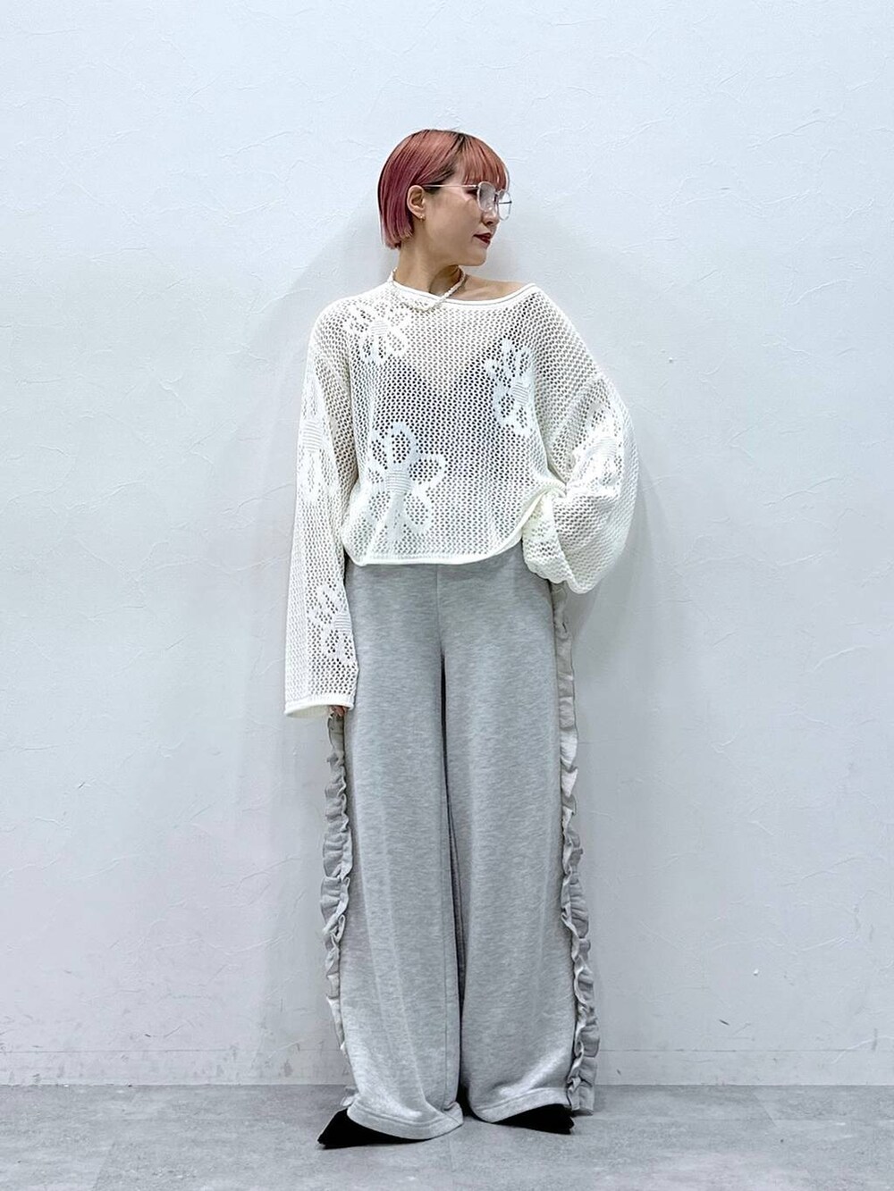 グレー系のスウェットパンツ、ホワイト系のニット/セーター、ホワイト系のネックレスを着用したレディースの春コーディネートの2枚目の写真
