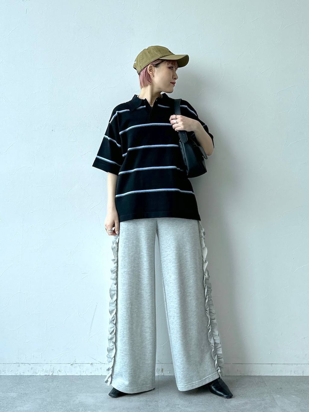 グレー系のスウェットパンツ、ブラック系のポロシャツ、ベージュ系のキャップを着用したレディースの春コーディネートの3枚目の写真