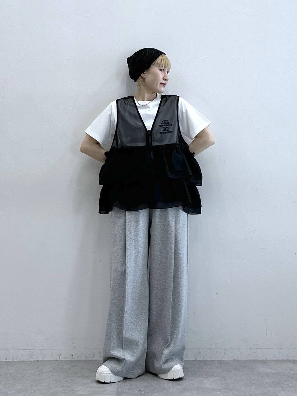 グレー系のスウェットパンツ、ホワイト系のTシャツ/カットソー、ブラック系のベストを着用したレディースの春コーディネートの2枚目の写真