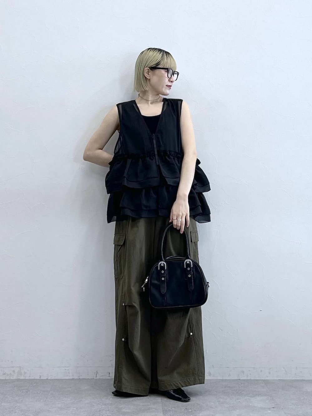 グリーン系のカーゴパンツ、ブラック系のタンクトップ、ブラック系のボストンバッグを着用したレディースの夏コーディネートの2枚目の写真