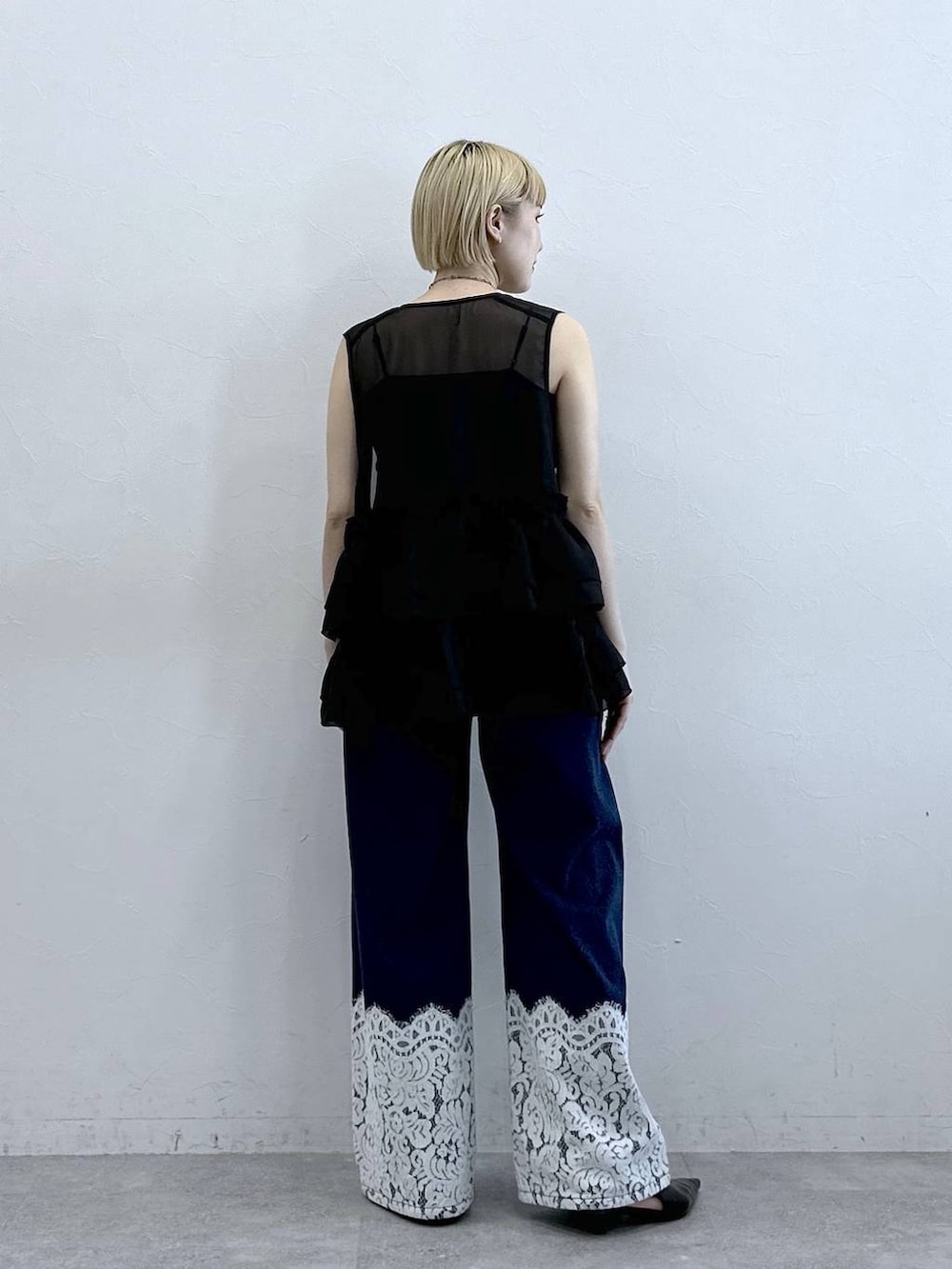 ブルー系のデニムパンツ、ブラック系のベスト、ブラック系のキャミソールを着用したレディースの春コーディネートの6枚目の写真
