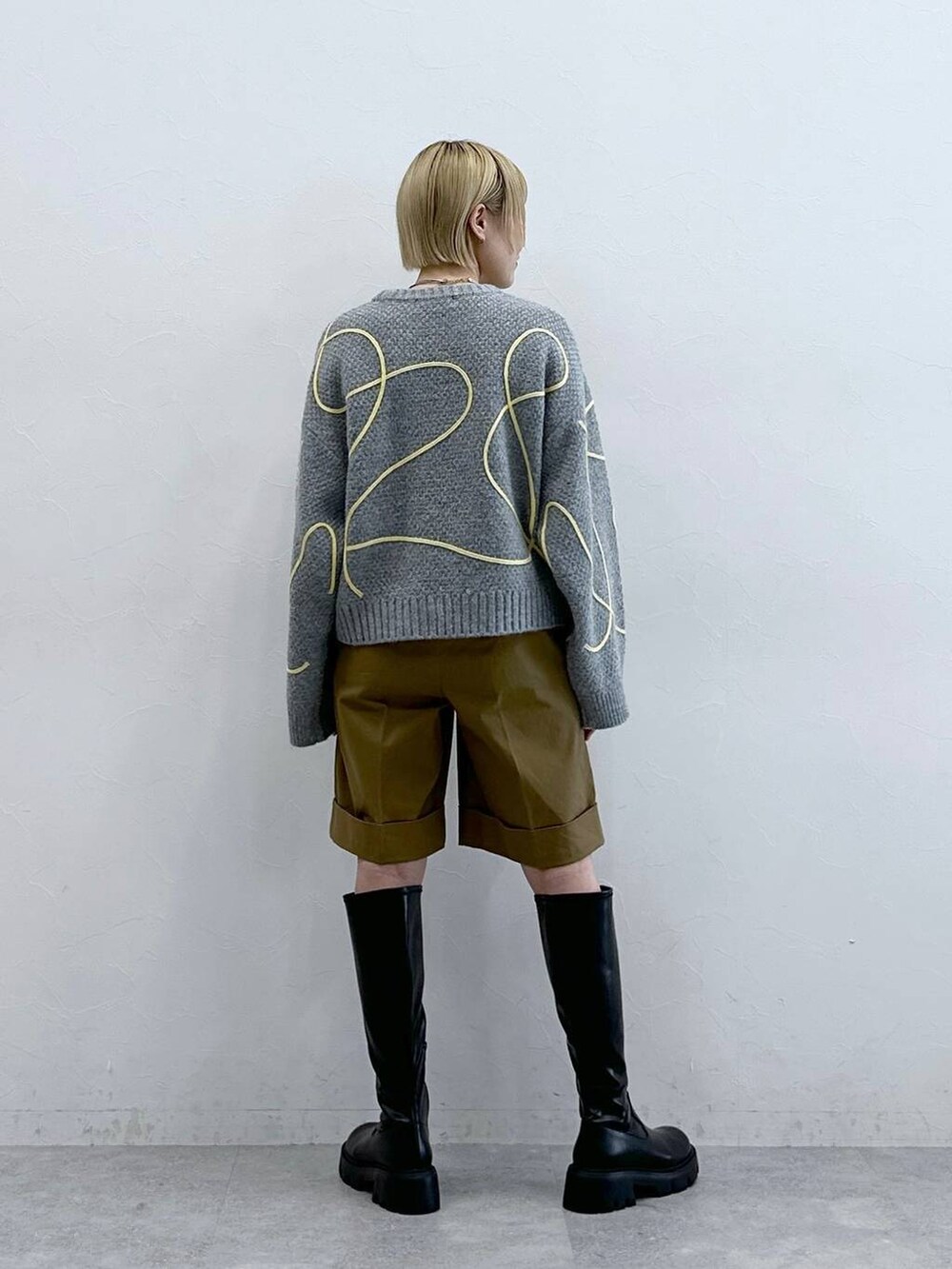 ブラック系のブーツ、ブラウン系のチノパンツ、グレー系のニット/セーターを着用したレディースの秋コーディネートの5枚目の写真