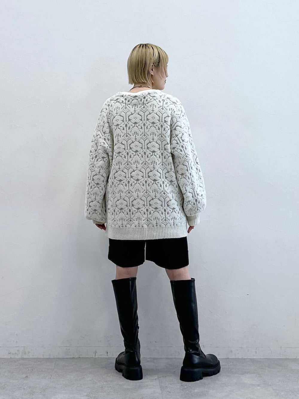 ブラック系のブーツ、ホワイト系のカーディガン/ボレロ、ブラック系のチノパンツを着用したレディースの秋コーディネートの5枚目の写真