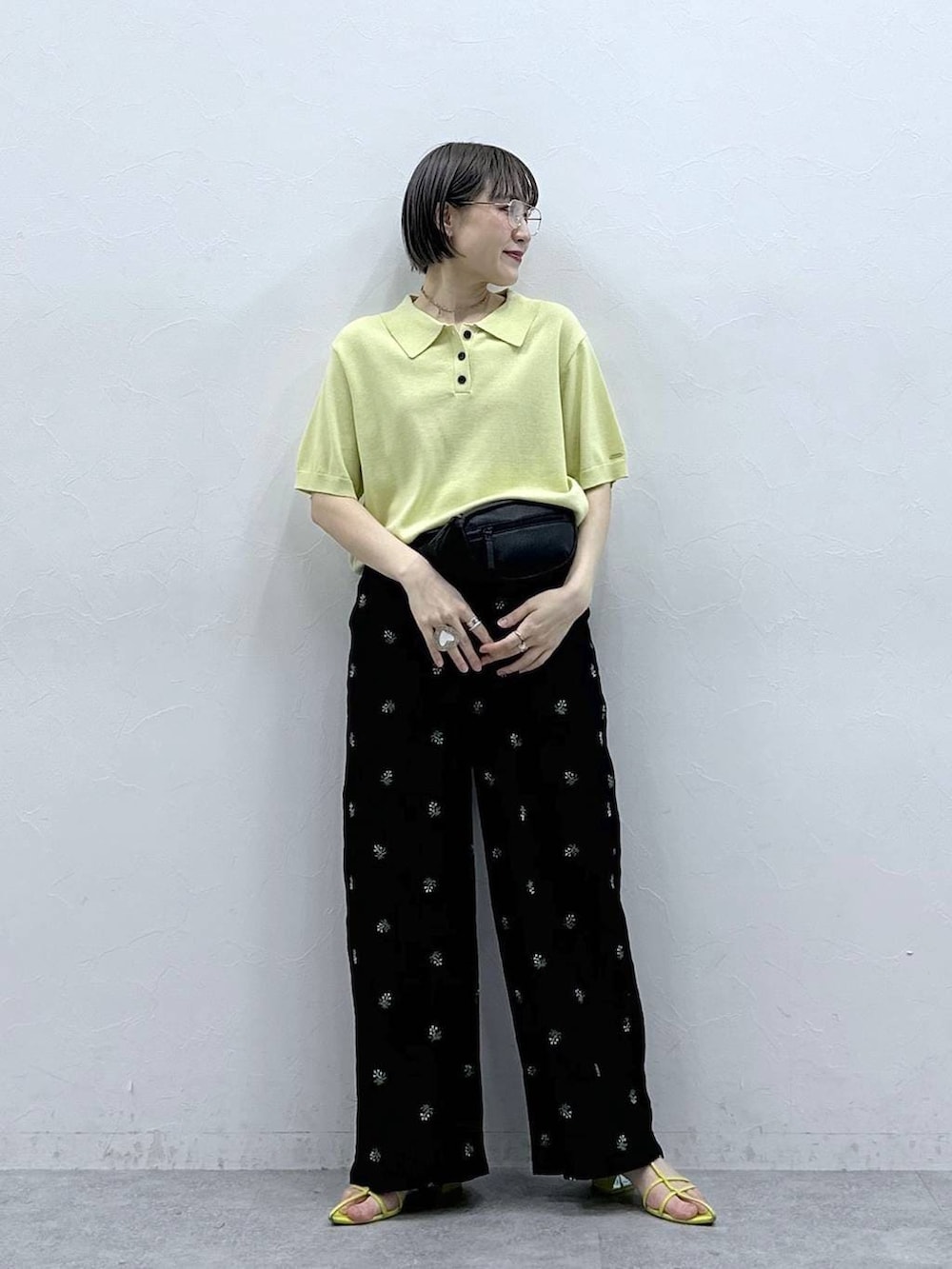 ブラック系のボディバッグ/ウエストポーチ、イエロー系のポロシャツ、ブラック系のスラックスを着用したレディースの春コーディネートの3枚目の写真