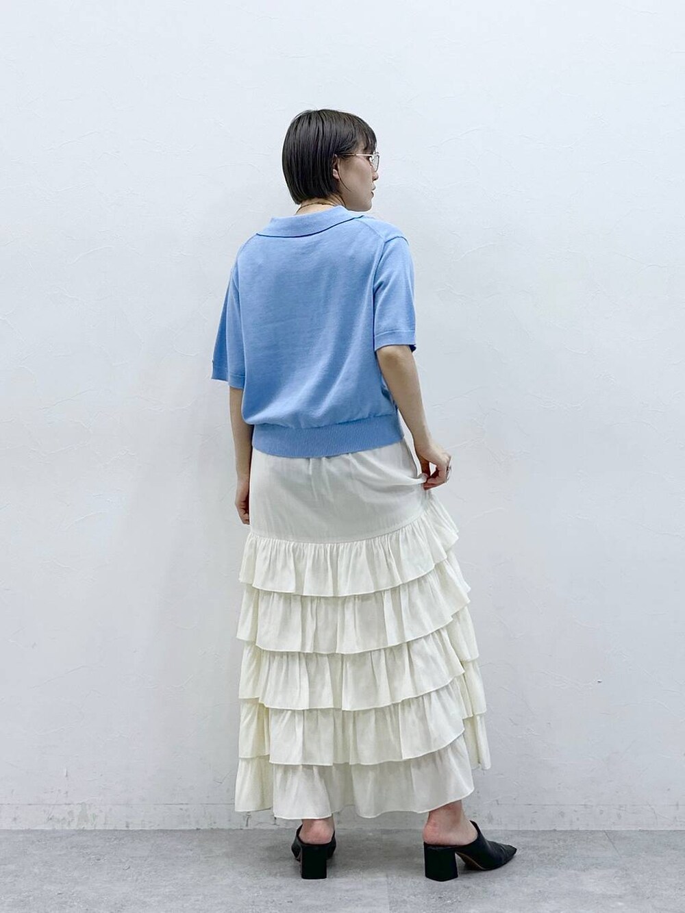 ブルー系のポロシャツ、ホワイト系のスカートを着用したレディースの春コーディネートの7枚目の写真