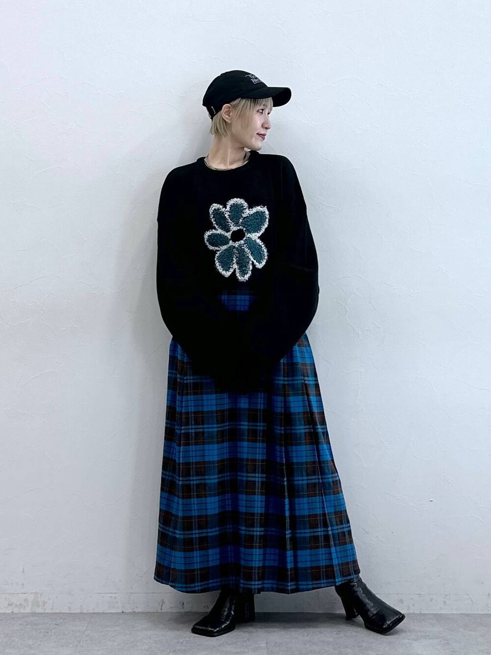 ブラック系のニット/セーター、ブルー系のスカート、ブラック系のキャップを着用したレディースの秋コーディネートの2枚目の写真