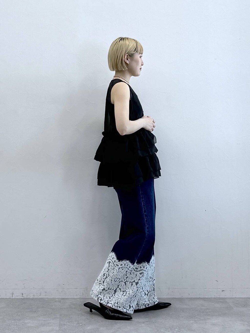 ブルー系のデニムパンツ、ブラック系のベスト、ブラック系のキャミソールを着用したレディースの春コーディネートの5枚目の写真
