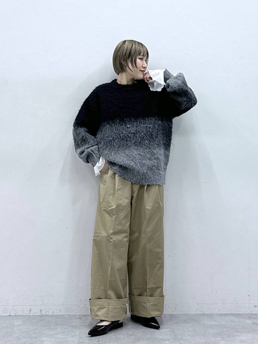 ブラック系のニット/セーター、ブラック系のパンプス、ベージュ系のチノパンツを着用したレディースの冬コーディネートの2枚目の写真