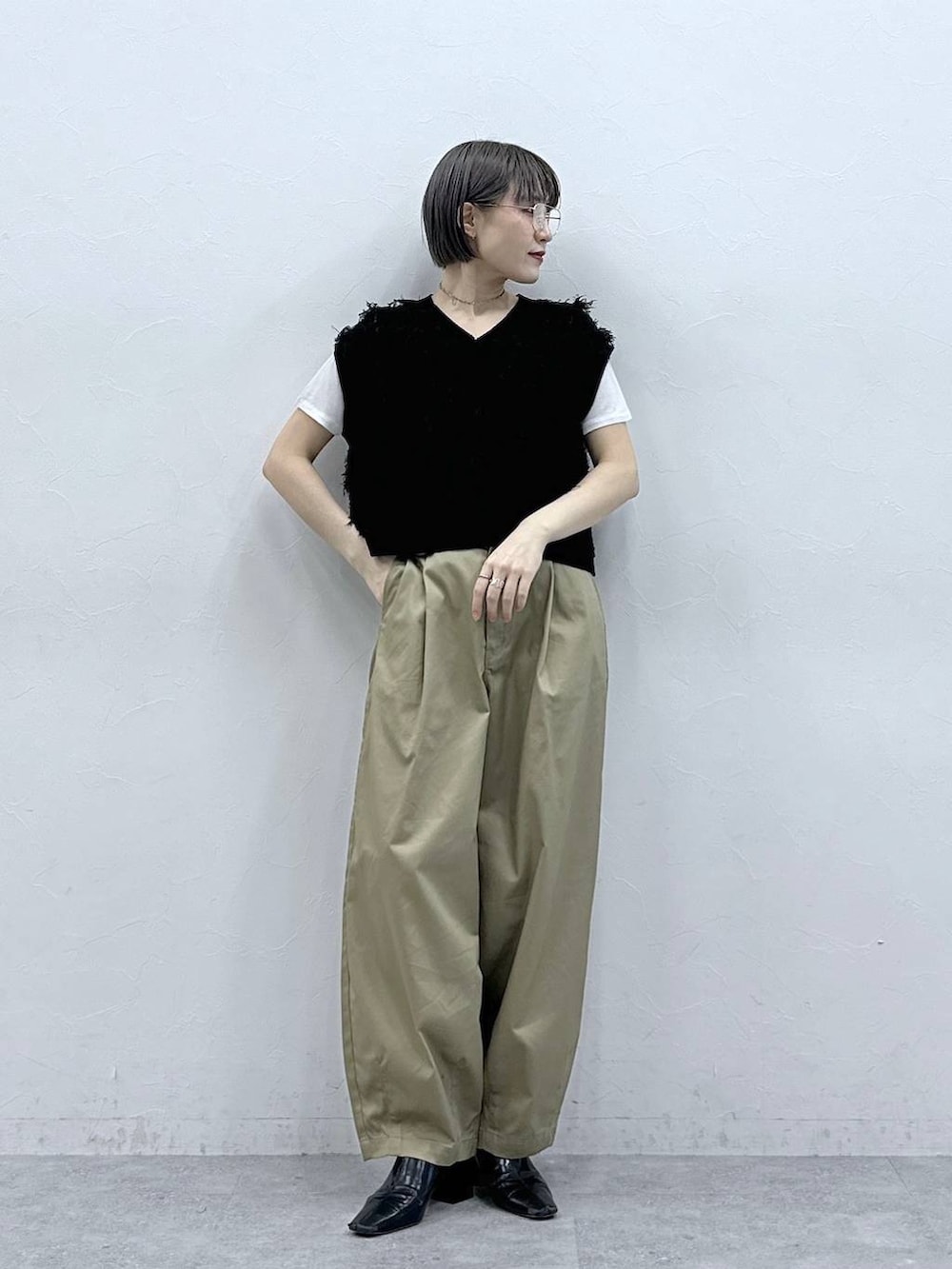 ベージュ系のチノパンツ、ホワイト系のTシャツ/カットソー、ブラック系のベストを着用したレディースの春コーディネートの3枚目の写真