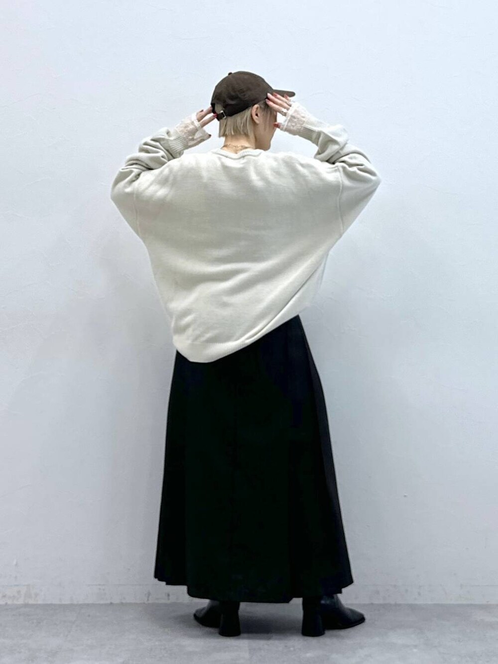 ホワイト系のニット/セーター、ブラウン系のスカート、ホワイト系のTシャツ/カットソーを着用したレディースの秋コーディネートの7枚目の写真