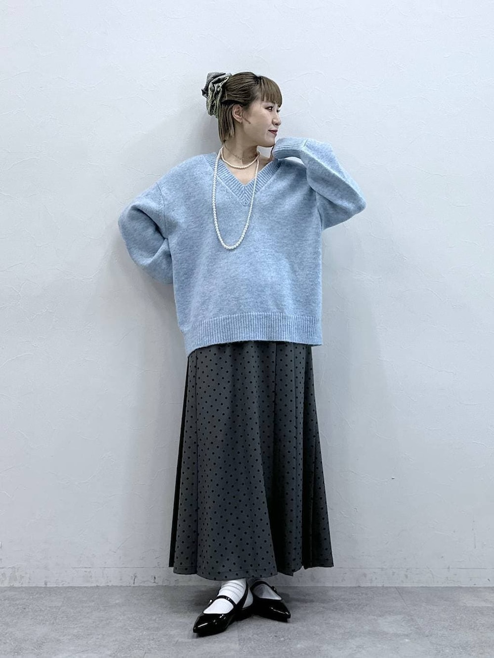 ブラック系のパンプス、ブルー系のニット/セーター、グレー系のスカートを着用したレディースの冬コーディネートの2枚目の写真