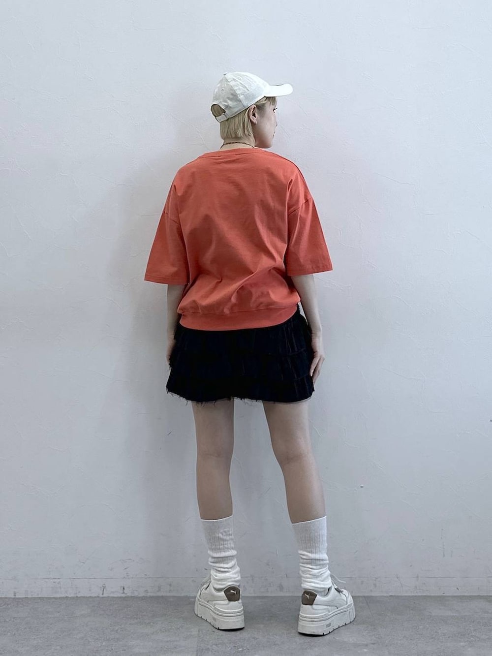 レッド系のTシャツ/カットソー、ブラック系のスカート、ホワイト系のキャップを着用したレディースの春コーディネートの5枚目の写真
