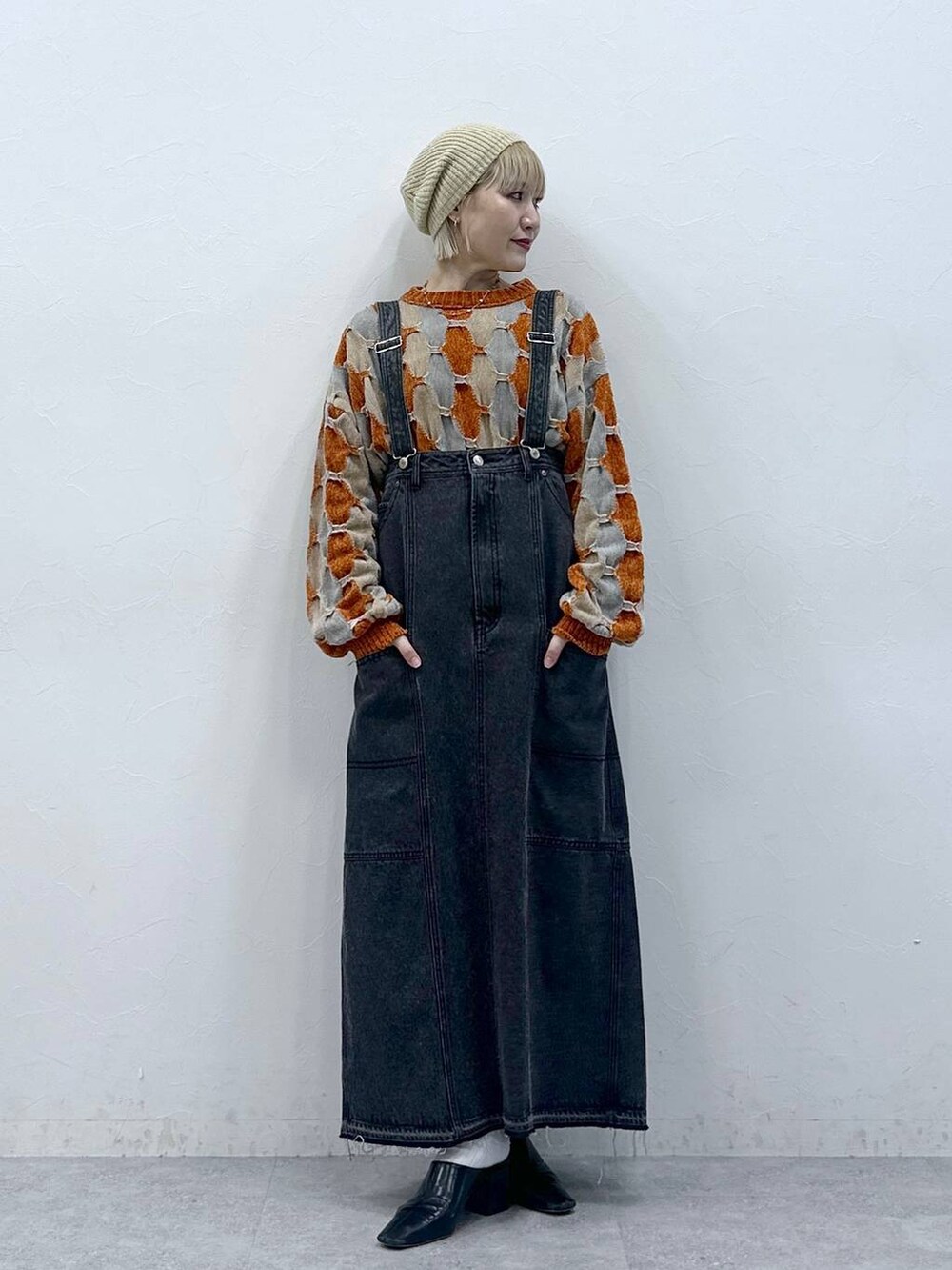 オレンジ系のニット/セーター、ブラック系のデニムスカート、ベージュ系のハンチング/ベレー帽を着用したレディースの秋コーディネートの3枚目の写真