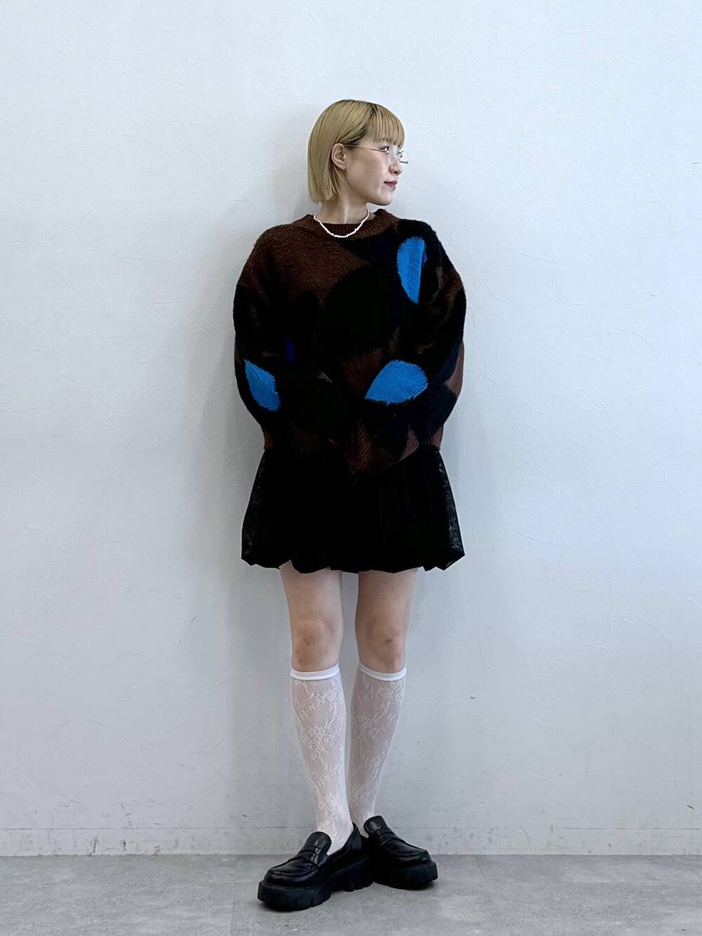 ブラック系のローファー、ブラック系のスカート、ブラウン系のニット/セーターを着用したレディースの夏コーディネートの2枚目の写真