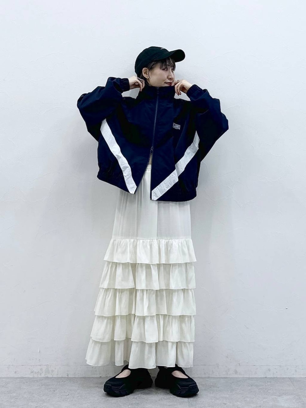 ブルー系のブルゾン、ホワイト系のスカート、ブラック系のキャップを着用したレディースの春コーディネートの2枚目の写真