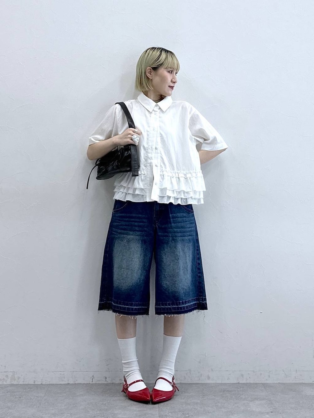 ブルー系のデニムパンツ、ブラック系のショルダーバッグ、レッド系のパンプスを着用したレディースの夏コーディネートの2枚目の写真