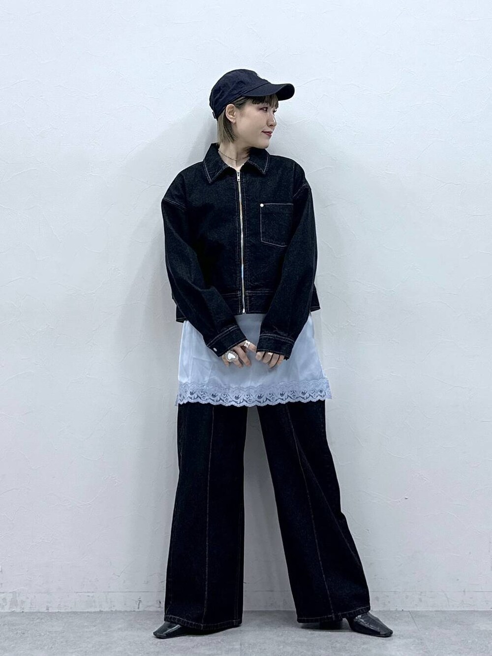 ブラック系のデニムジャケット、ブラック系のデニムパンツ、ブルー系のキャミソールを着用したレディースの冬コーディネートの3枚目の写真