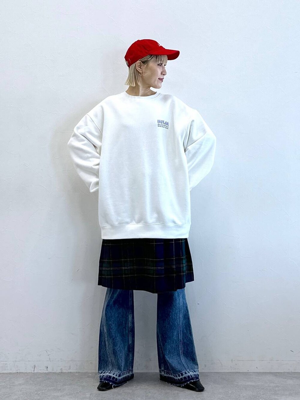 グリーン系のスカート、ブルー系のデニムパンツ、ホワイト系のスウェットを着用したレディースの秋コーディネートの2枚目の写真