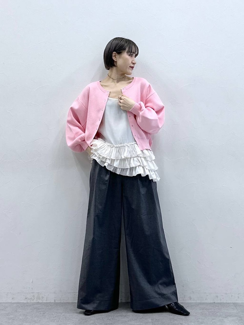 ホワイト系のキャミソール、ピンク系のカーディガン/ボレロ、グレー系のスラックスを着用したレディースの春コーディネートの3枚目の写真